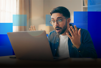 A man reacting with surprise while looking at his laptop screen