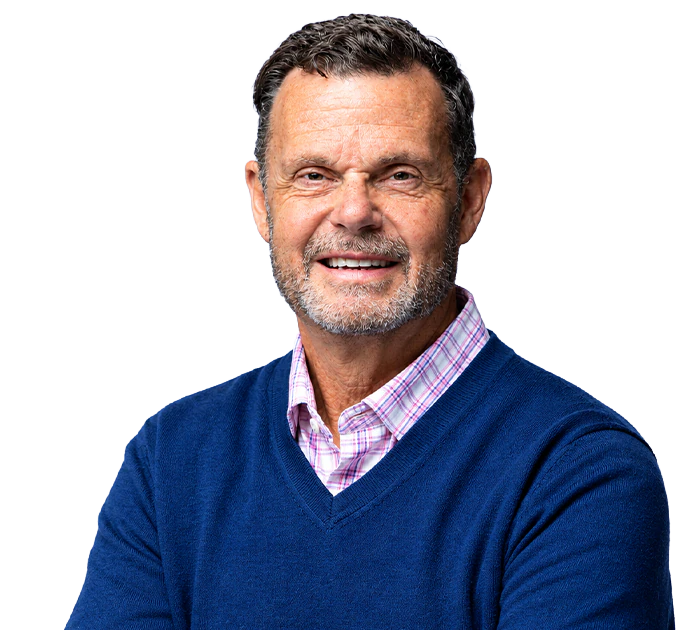 Ron Kane smiling, wearing a navy V-neck sweater over a pink checked collared shirt