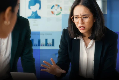 Colleagues discuss business reports, with one woman looking concerned.
