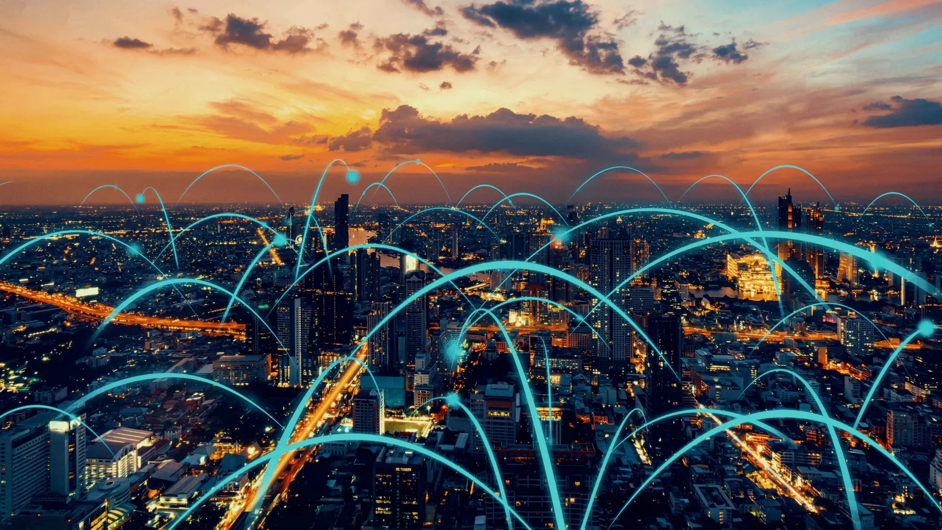 A city skyline at sunset is overlaid with digital network lines, symbolizing connectivity and technology in urban landscapes.