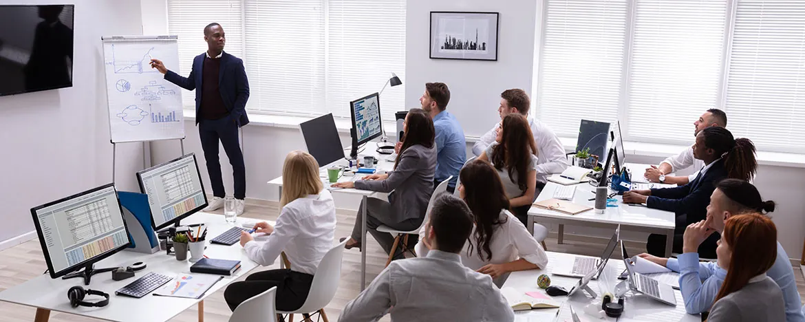 A diverse team of professionals attentively listening to a presenter in a modern office during a business meeting.