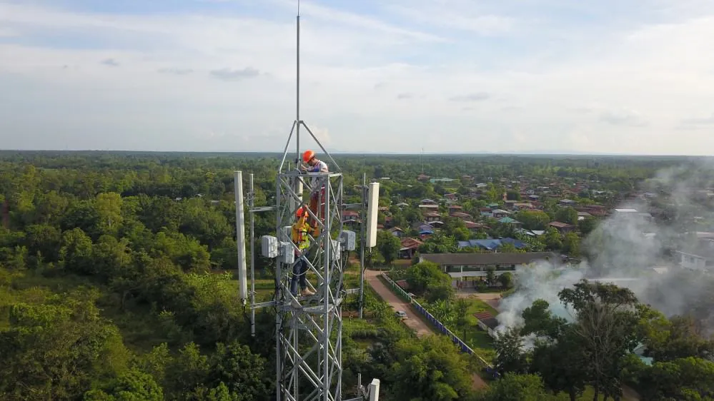 a uniformed man working on top of a telecom tower