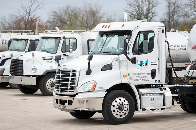 A fleet of liquid transport trucks lined up, featuring a prominent white truck